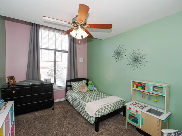 Carpeted room featuring a ceiling fan with integrated lighting, a window with blinds and drapes, and multi-toned walls