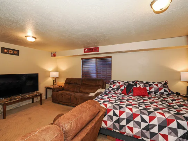 Carpeted room featuring a window with horizontal blinds, built-in structural beam, and two ceiling-mounted light fixtures