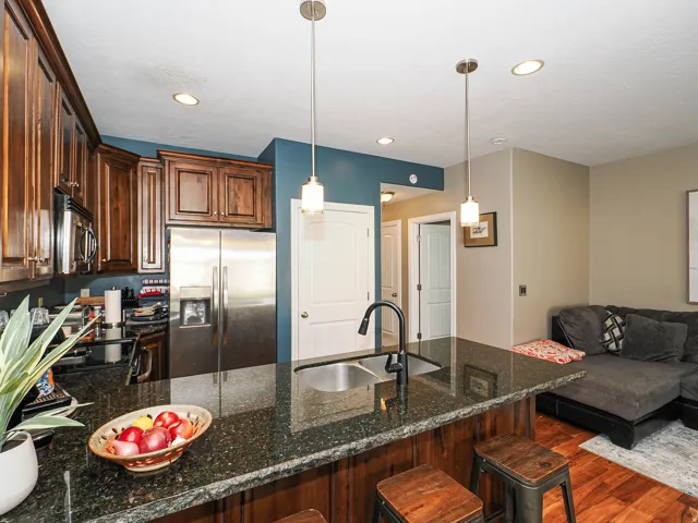 Kitchen island featuring a dark speckled countertop, undermount stainless steel sink, and a black gooseneck faucet