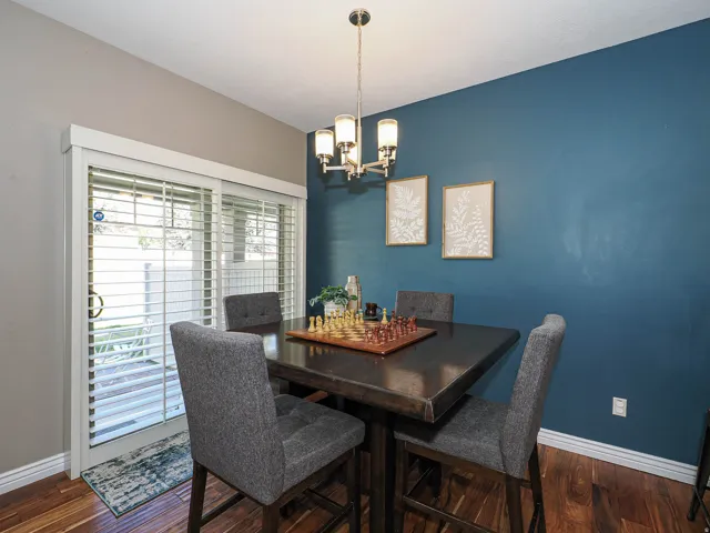 Dining area featuring wood-finish flooring, a contemporary chandelier, and a sliding glass door with interior plantation shutters