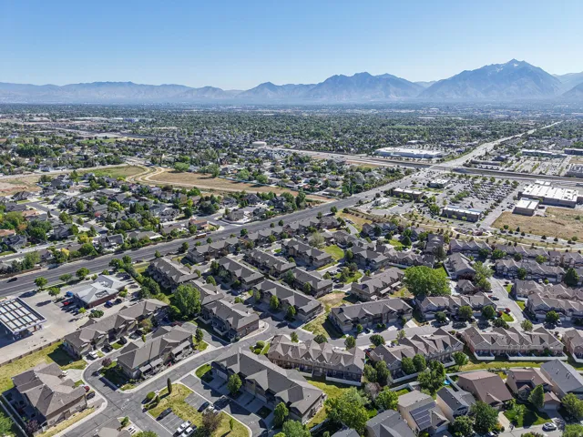 Expansive aerial perspective showcasing a residential community with varied architectural styles, mature landscaping, and mountain backdrop