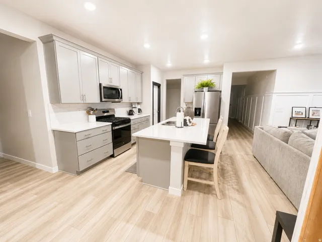Modern kitchen featuring light gray cabinetry, stainless steel appliances, white subway tile backsplash, and a central island with countertop seating