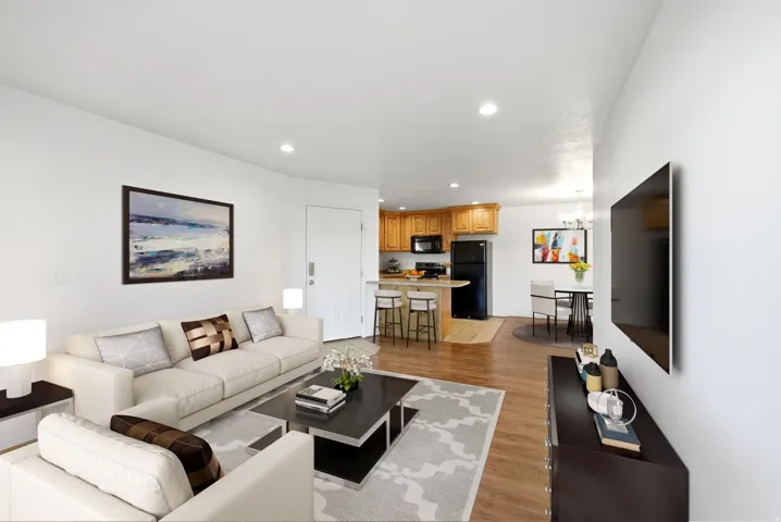 Open concept living space featuring wood-finish flooring, recessed lighting, a breakfast bar with built-in cabinetry, and a dedicated dining area with chandelier