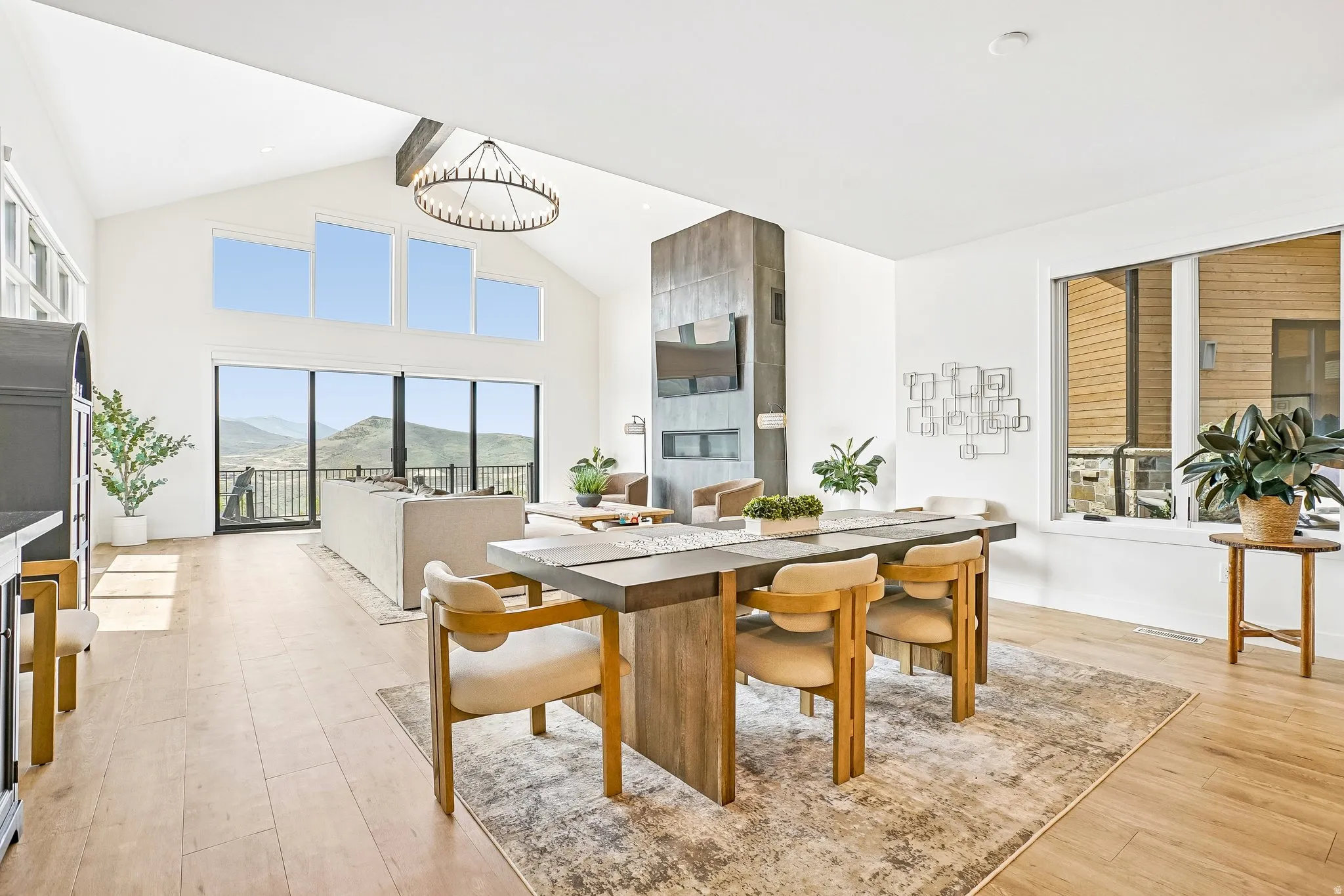 Spacious open-concept interior featuring high vaulted ceilings, wood-finish flooring, and a prominent stone-clad fireplace