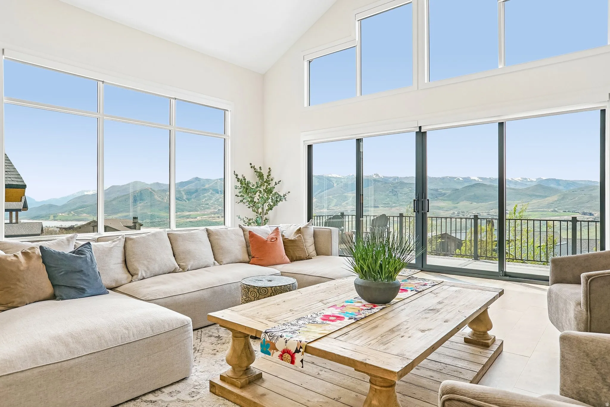 Vaulted ceiling living space featuring expansive windows, wood-finish flooring, and direct access to an exterior deck