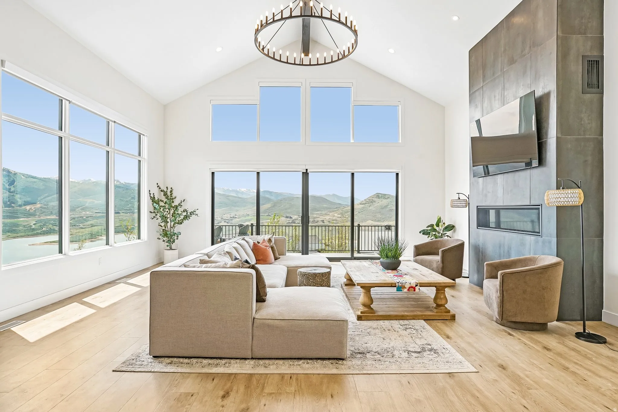 Vaulted living space featuring extensive window lines, wood-finish flooring, and a modern fireplace with a dark-toned surround