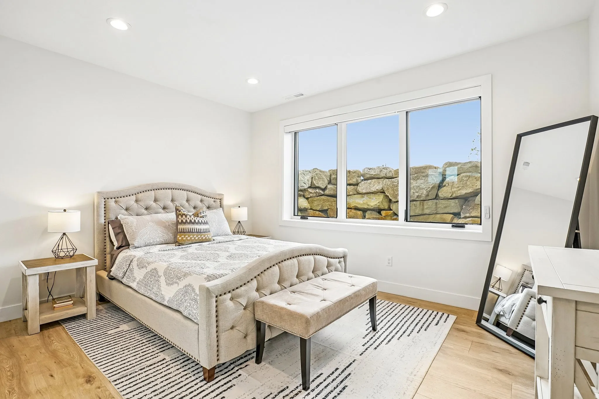 Bright room featuring wood-finish flooring, recessed lighting, and a large window with a stone wall backdrop
