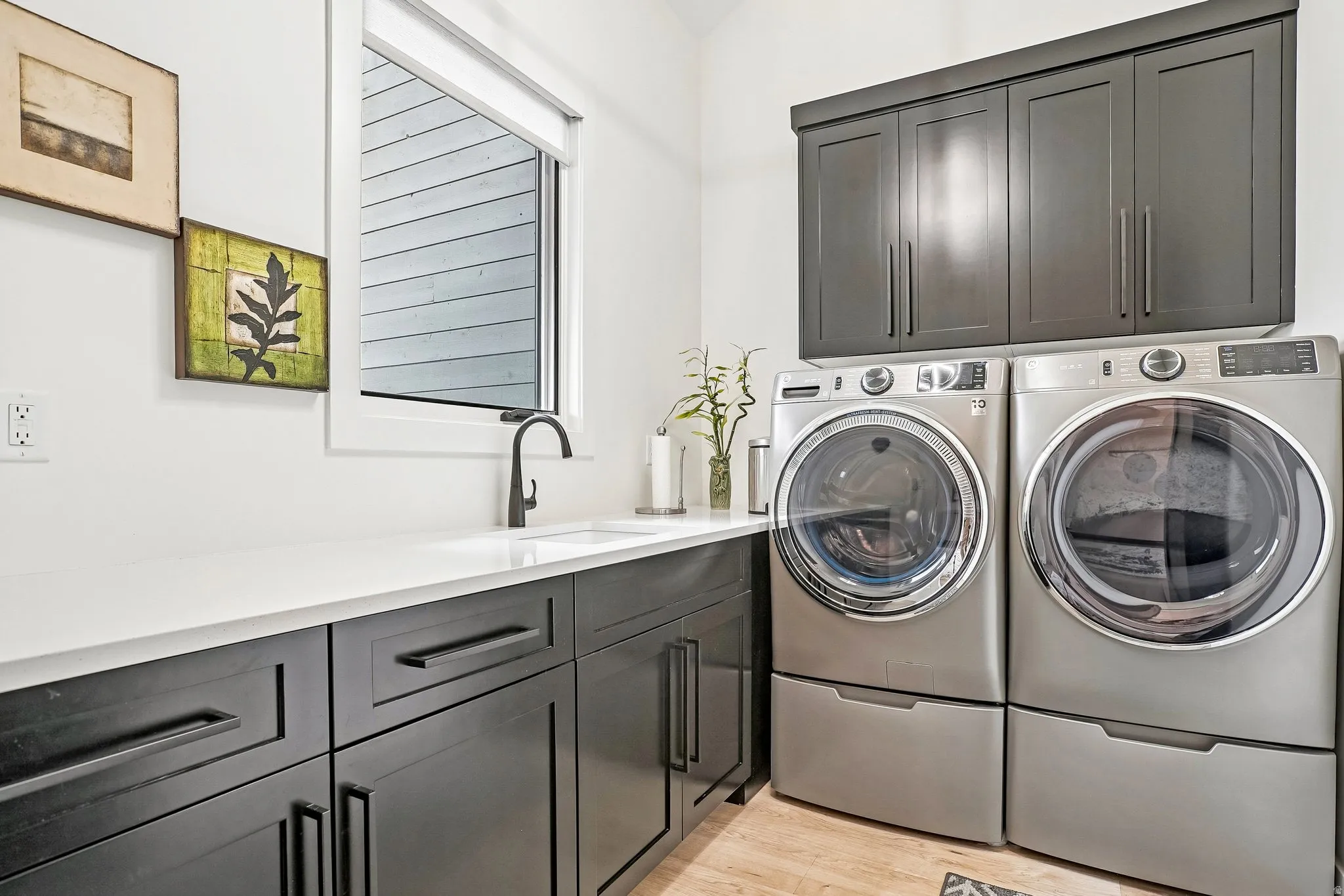Laundry area featuring a window, built-in cabinetry, white countertop, and sink with a black faucet