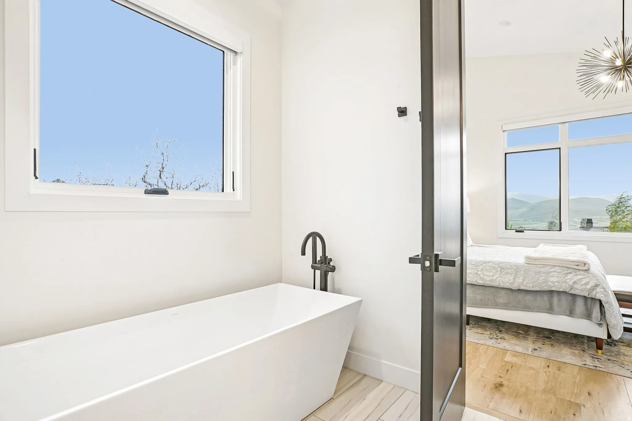 Freestanding soaking tub with a black wall-mounted faucet