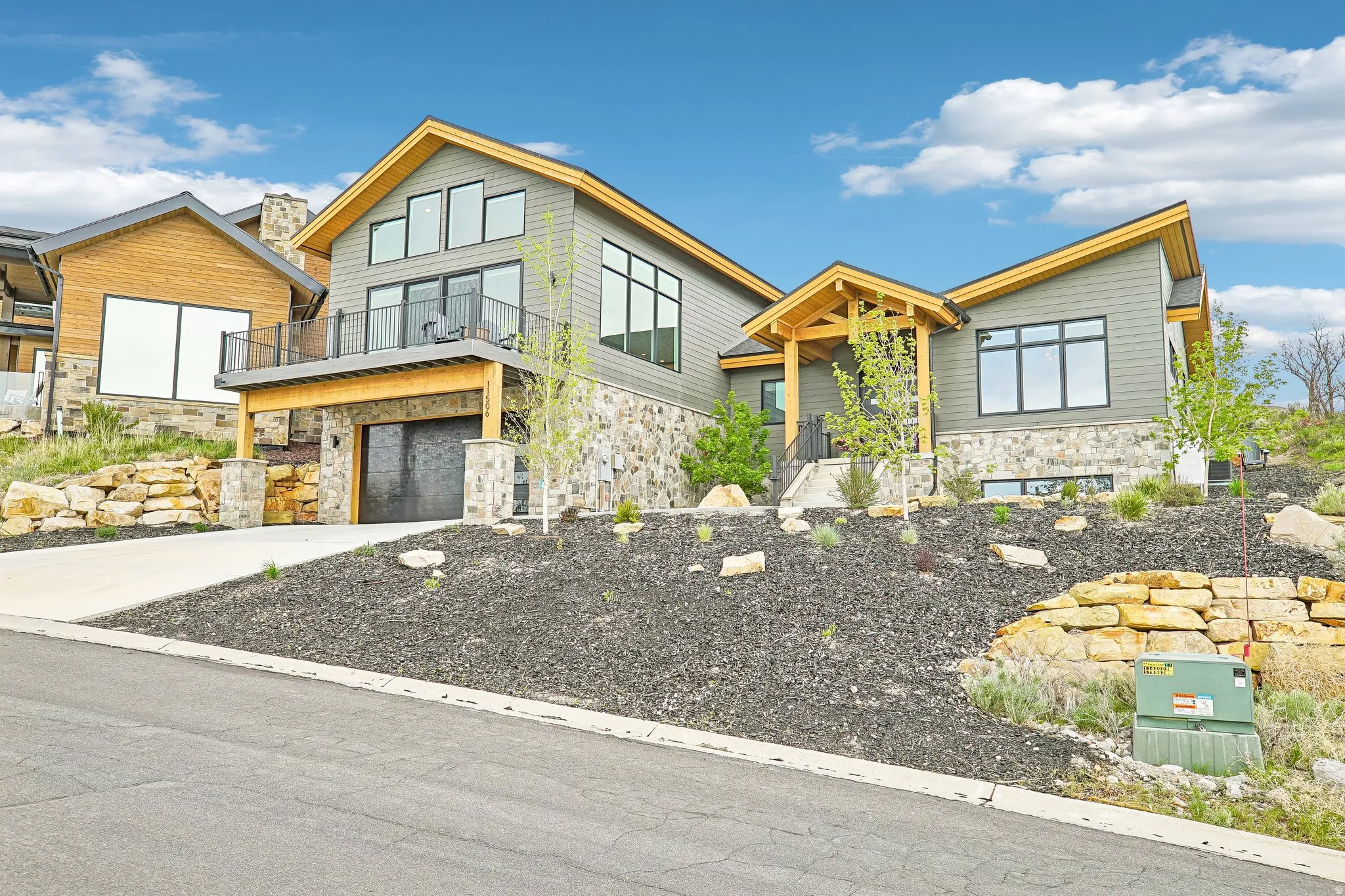 Modern architectural home featuring a grey siding exterior with stone accents