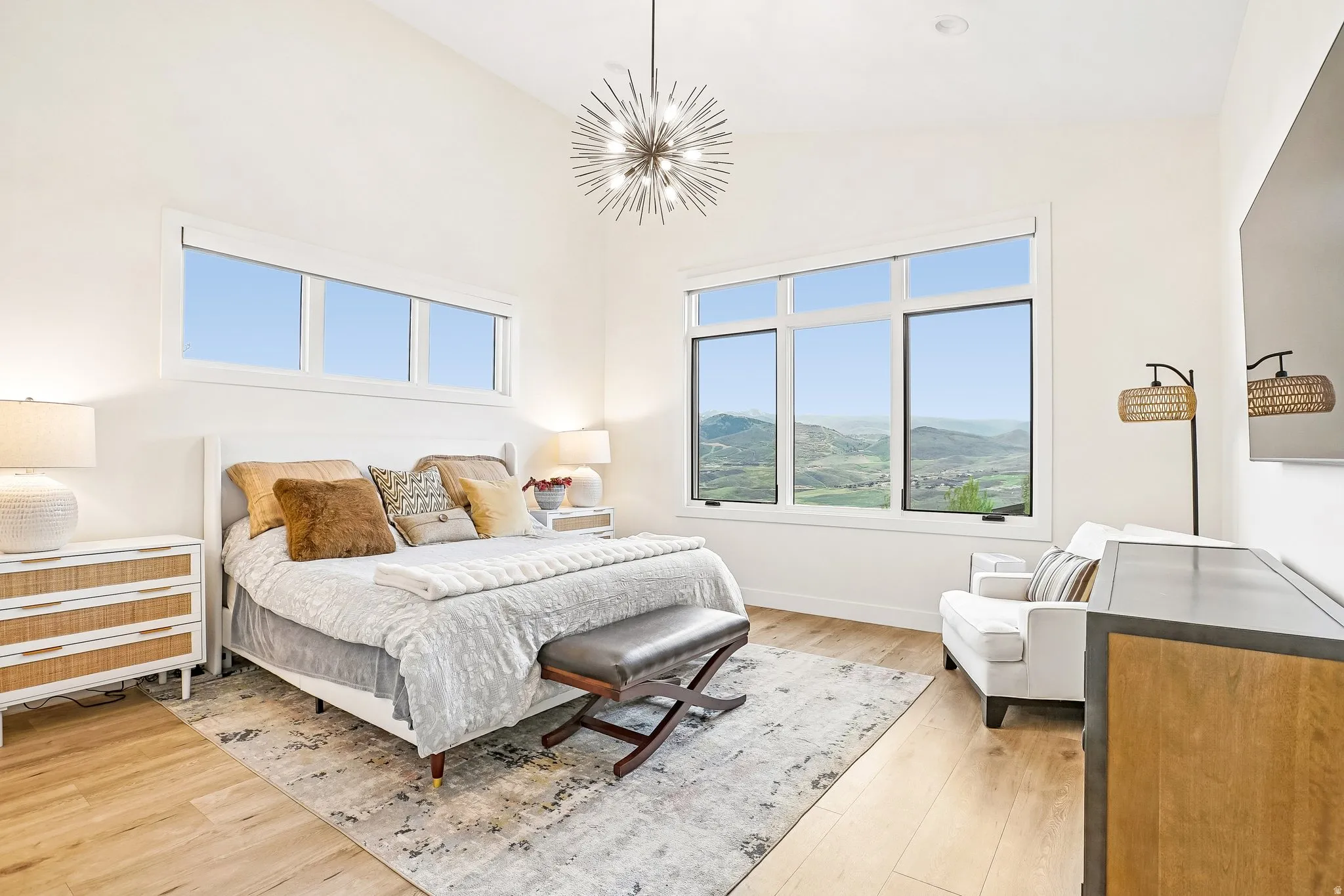 Vaulted ceiling bedroom featuring large windows, wood-finish flooring, and a contemporary chandelier