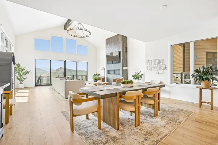 Spacious open-concept interior featuring high vaulted ceilings, wood-finish flooring, and a prominent stone-clad fireplace