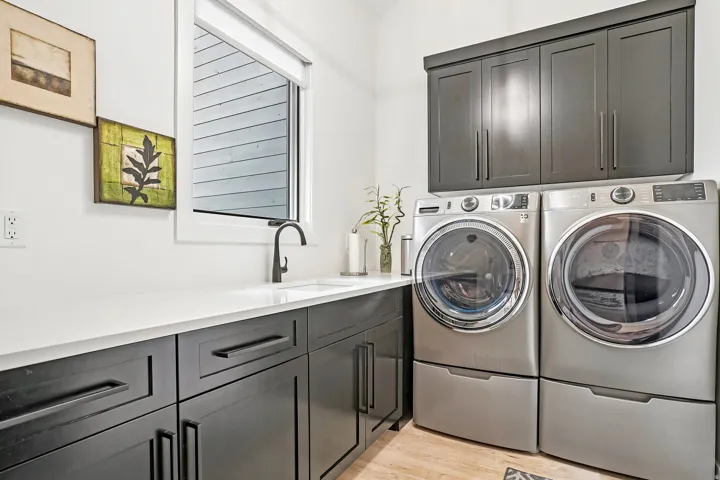 Laundry area featuring a window, built-in cabinetry, white countertop, and sink with a black faucet