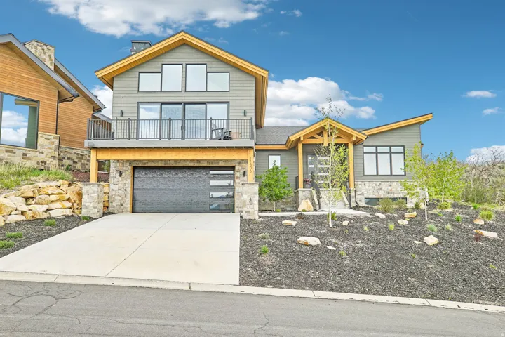 Contemporary two-story residence featuring a dark gray siding exterior with stone accents and natural wood trim