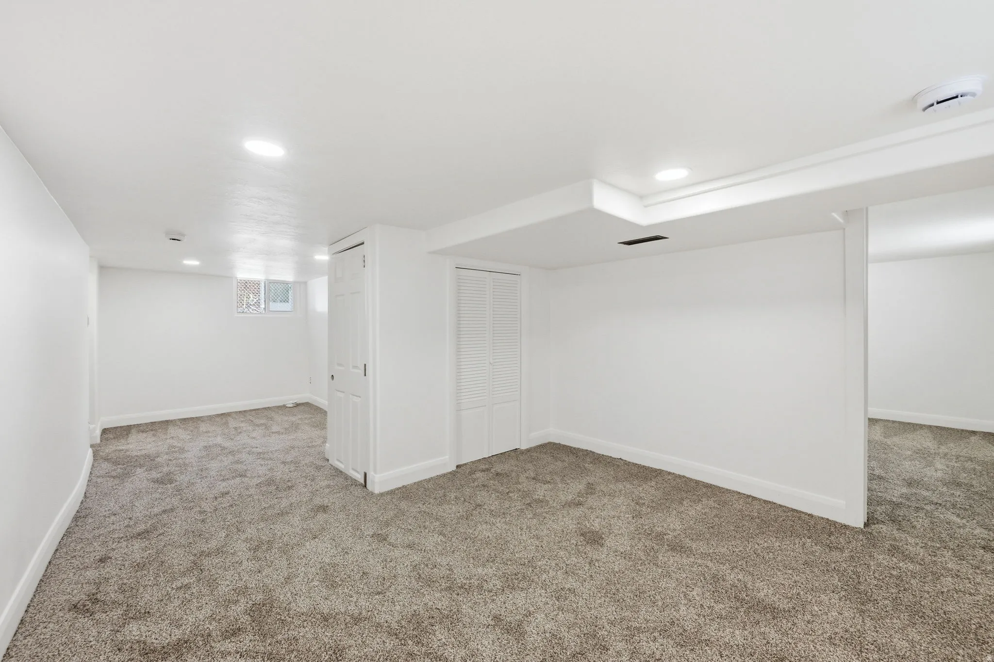 Spacious interior featuring neutral carpeting, white walls, recessed lighting, and white trim
