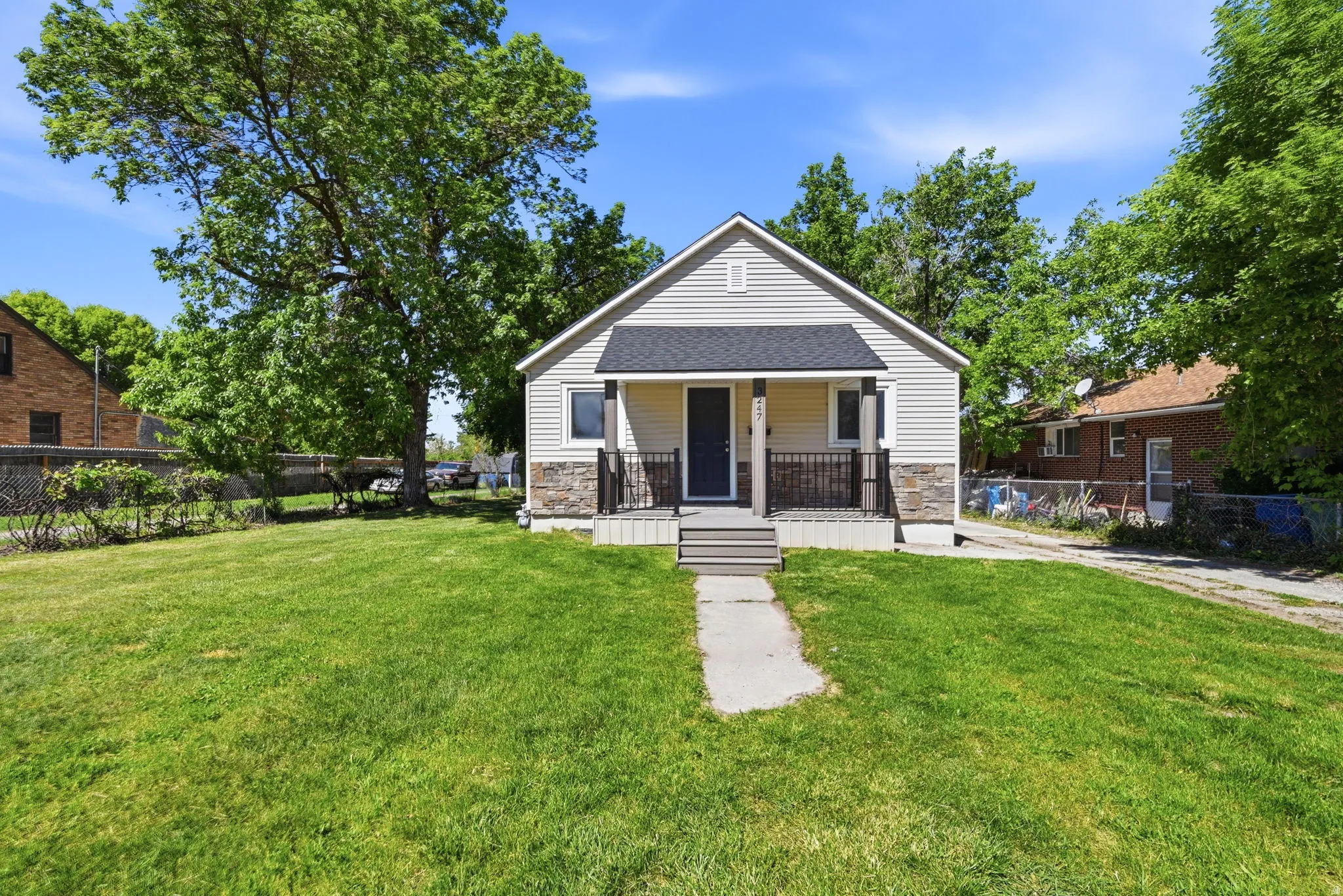 Siding exterior with stone accents, a covered front porch, and a concrete walkway