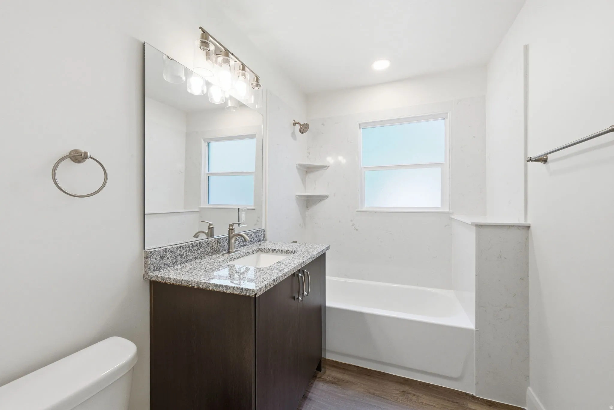 Full bathroom featuring a dark wood-finish vanity with a granite countertop, undermount sink, and brushed nickel fixtures