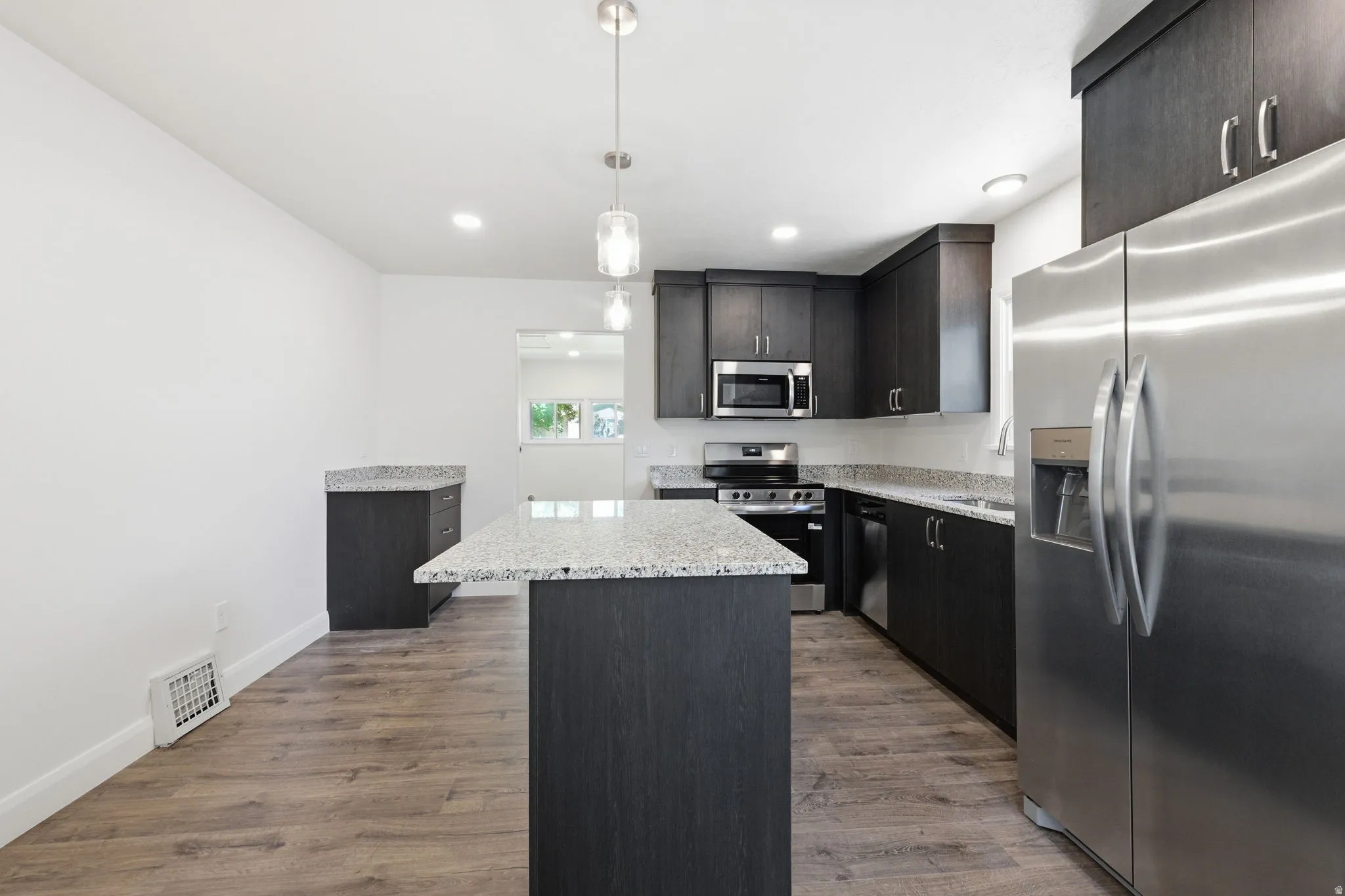 Kitchen featuring dark wood-finish cabinetry, light-toned countertops, and stainless steel appliances