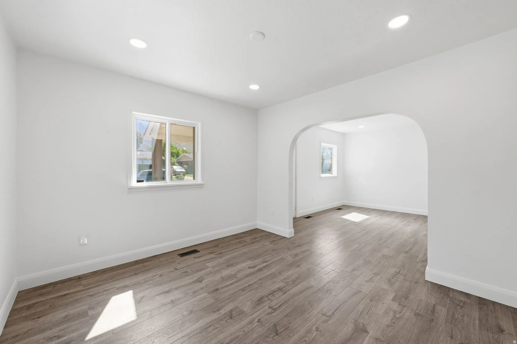 Expansive interior space featuring wood-finish flooring, recessed lighting, and a white color palette