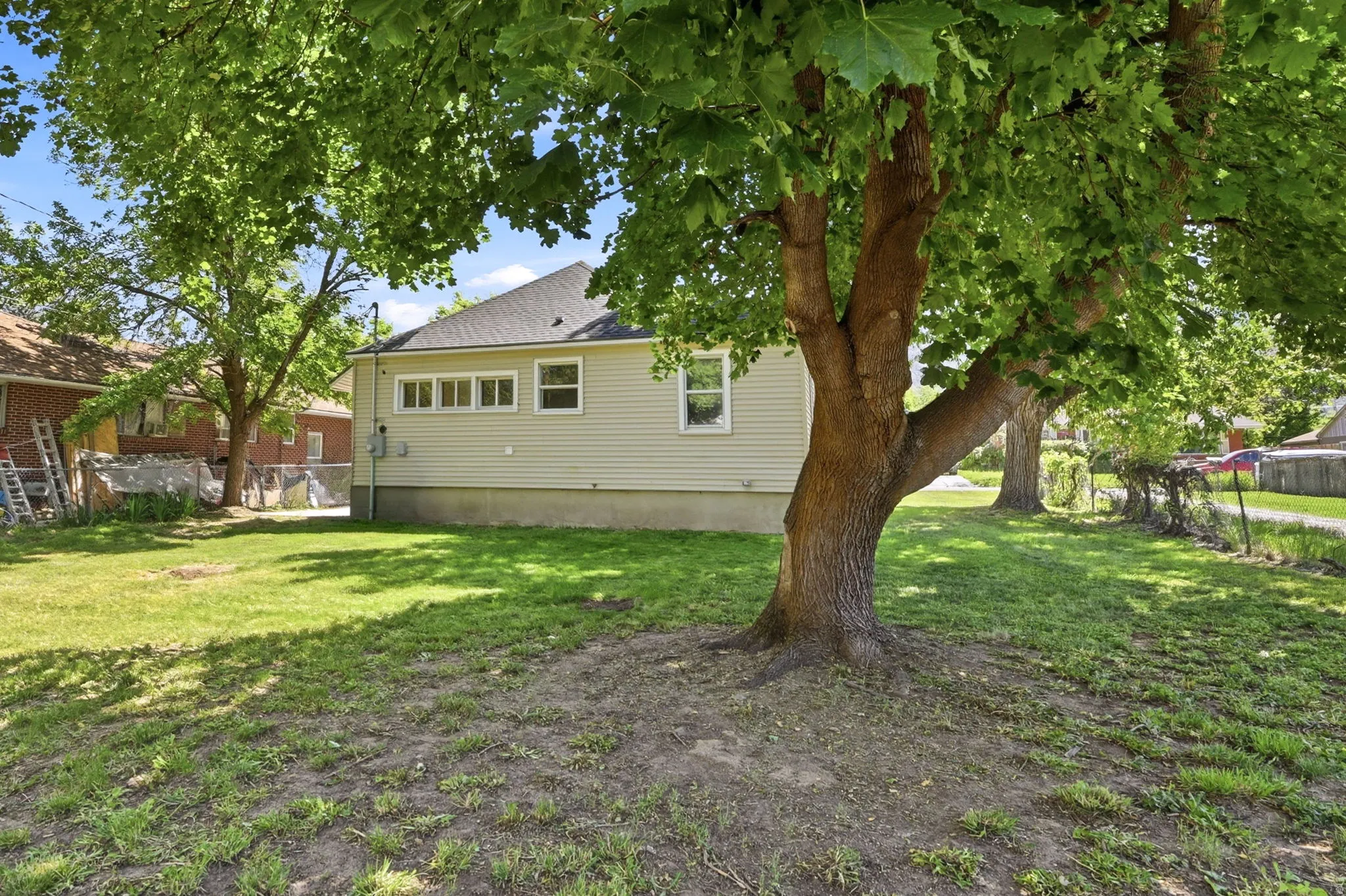 Spacious backyard featuring mature trees providing ample shade and a manicured lawn