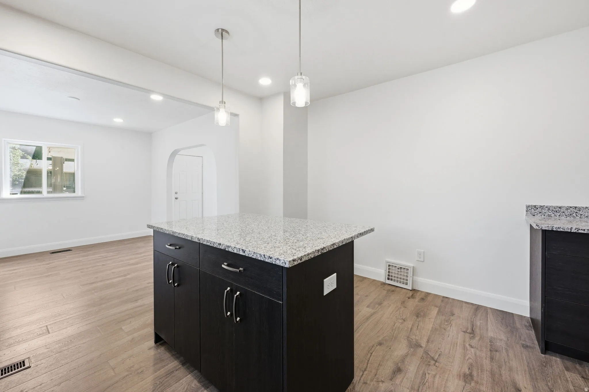Kitchen island with a light-toned stone countertop and dark cabinetry