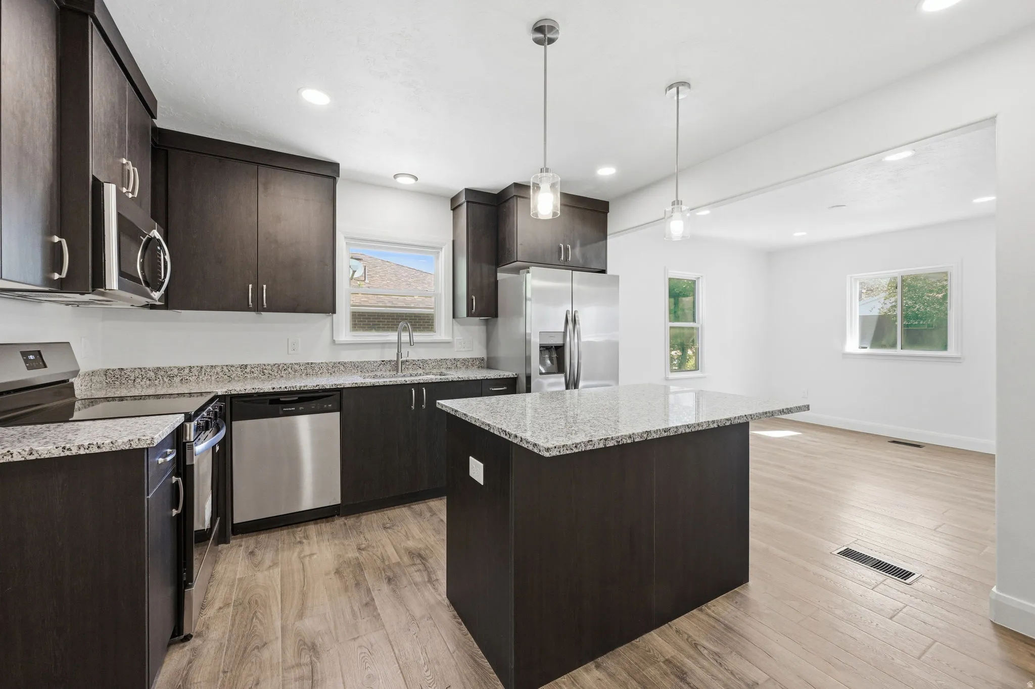 Modern kitchen featuring dark wood-finish cabinetry, stainless steel appliances, and light-toned countertops