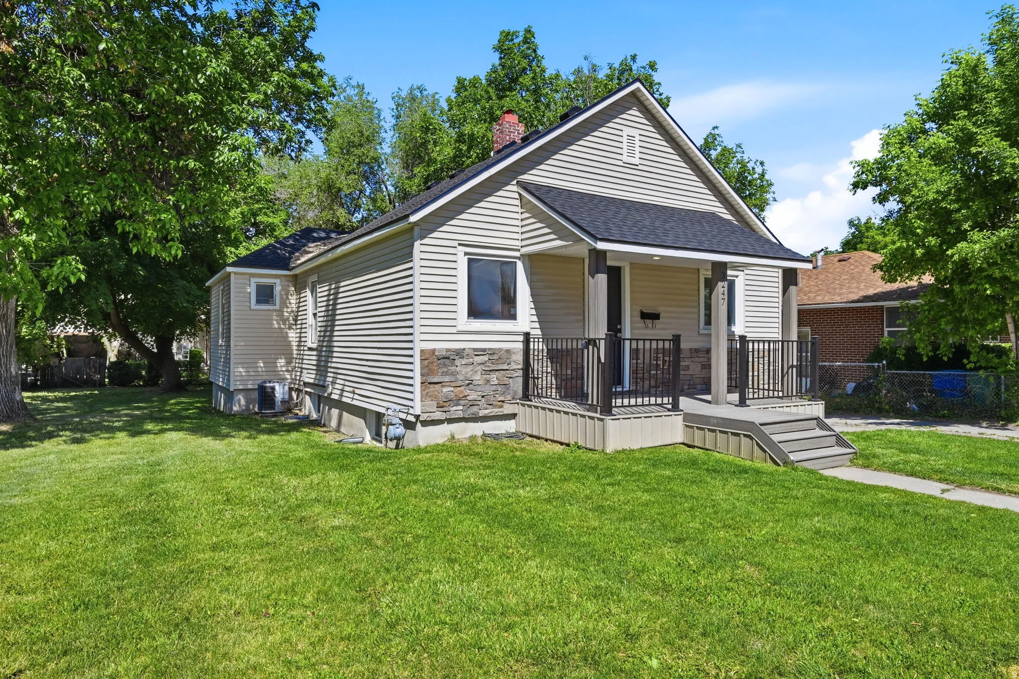 Exterior featuring light-colored siding, a stone accent foundation, and a covered front porch with dark railings