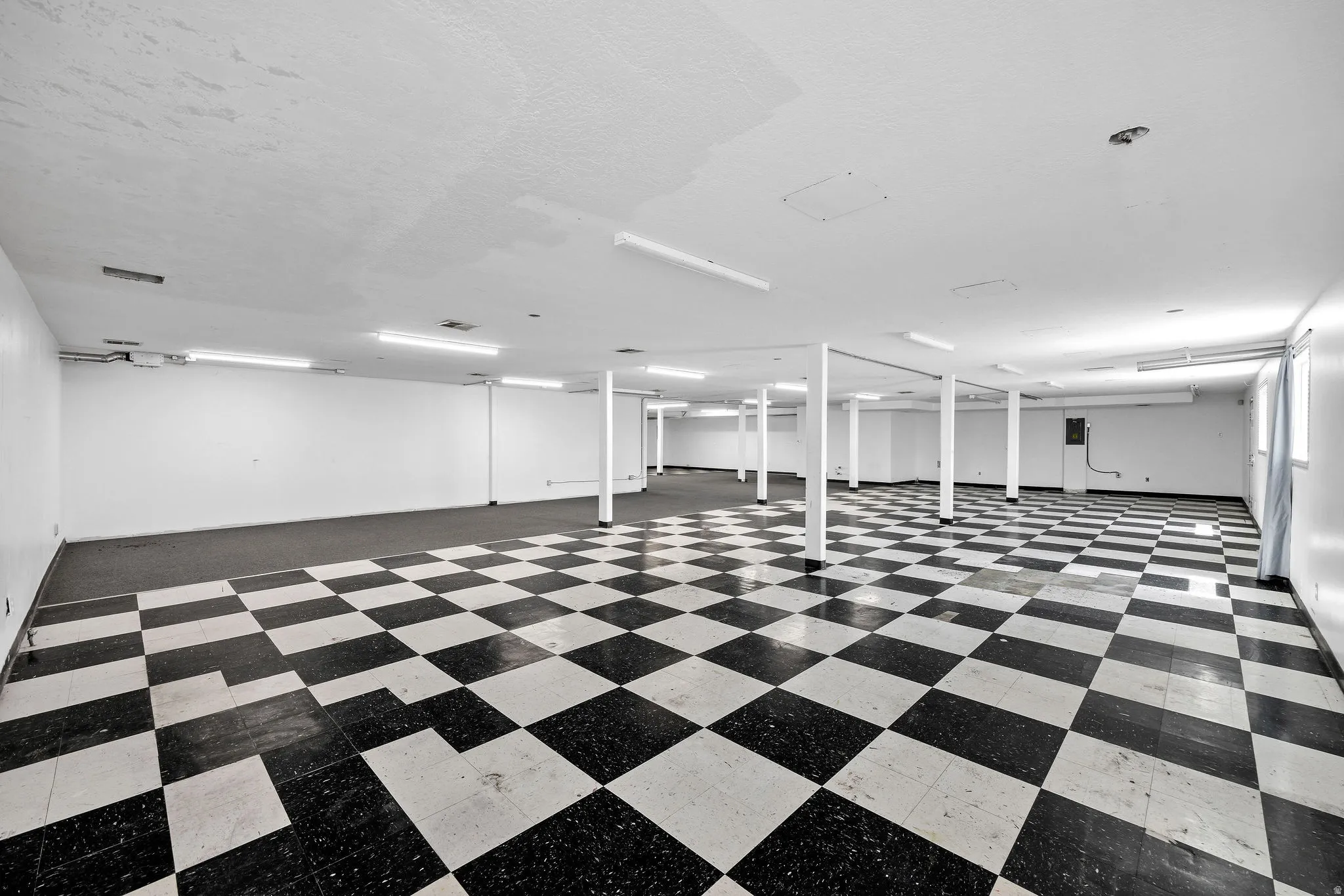 Expansive open space featuring checkerboard tile flooring and recessed lighting