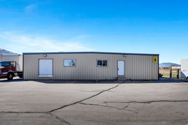 Freestanding industrial building featuring corrugated metal siding, a single roll-up door, two exterior windows, and a pedestrian entry door