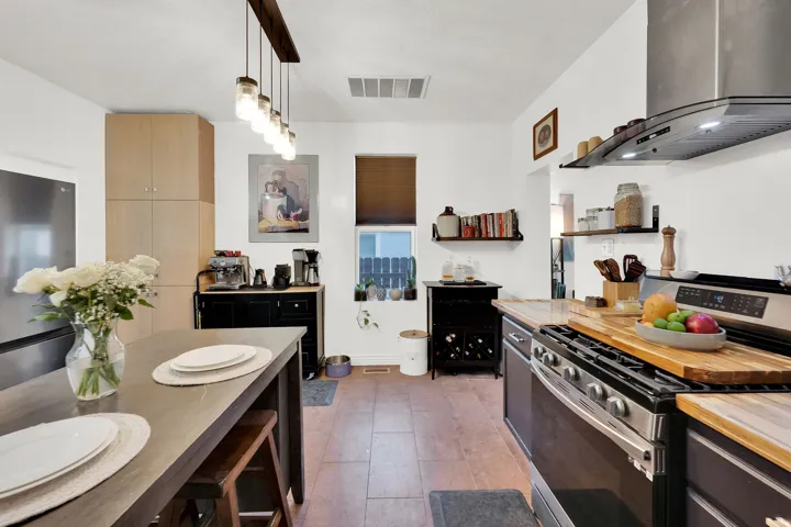 Contemporary kitchen featuring wood-finish flooring, light wood-tone cabinetry, and stainless steel appliances