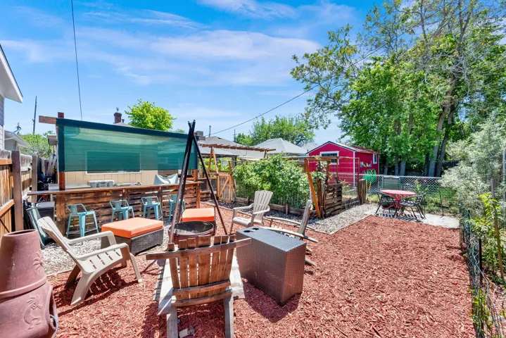 Outdoor entertainment space with a built-in bar, overhead shade structure, and a red garden shed