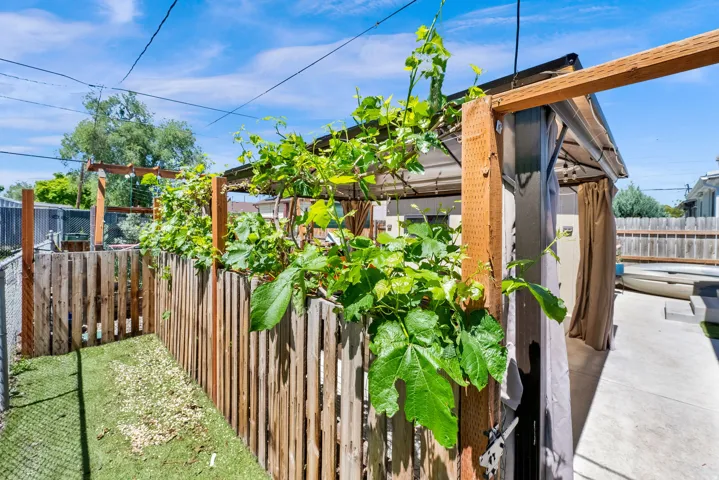Outdoor living area featuring a covered patio structure, a wooden privacy fence, and concrete paving