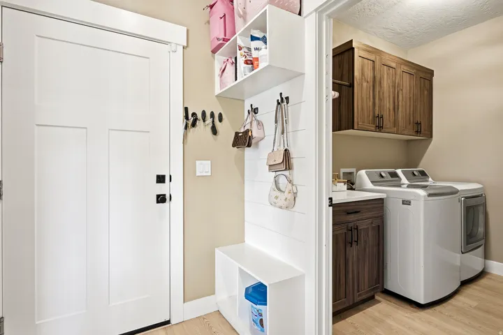 Mudroom area featuring a white built-in bench with storage, shiplap accent wall, and integrated shelving