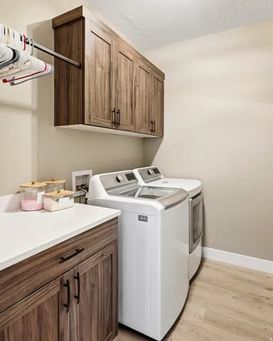 Laundry area featuring wood-finish cabinetry, a white countertop, and light wood-finish flooring