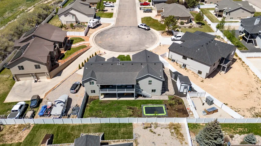 Contemporary residence with a dark shingle roof, light-colored siding, and a rear balcony overlooking a green lawn