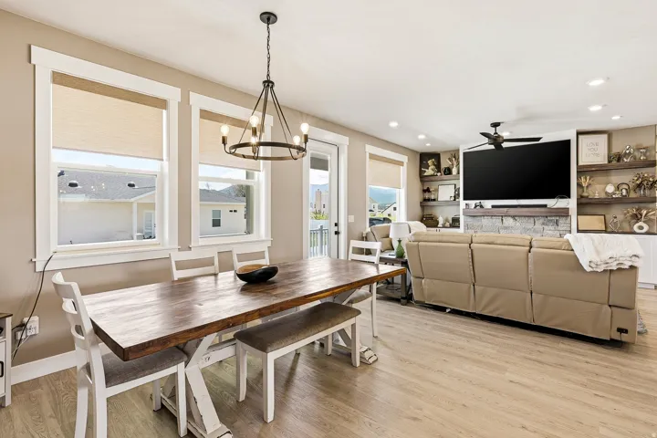 Open-concept living area featuring wood-finish flooring, a contemporary chandelier, recessed lighting, and a built-in media center with shelving