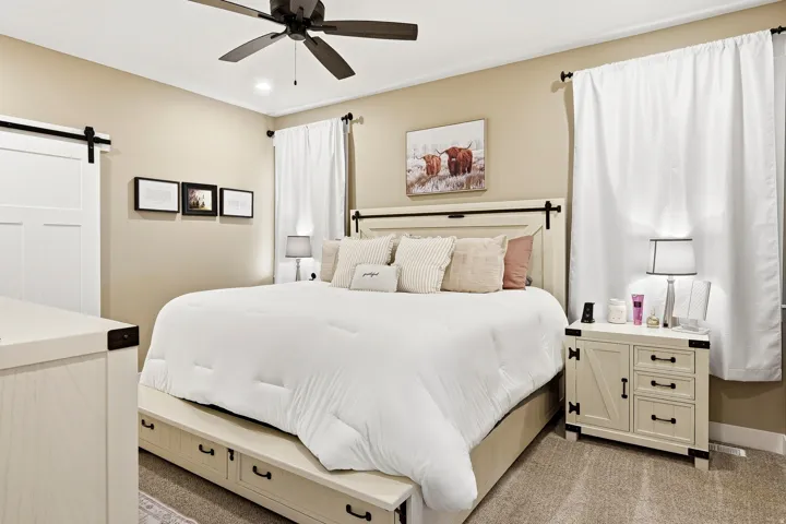 Room featuring a ceiling fan, a barn door, and a built-in storage bed frame
