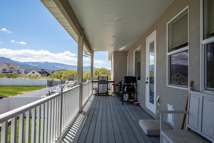 Covered outdoor patio featuring composite decking, white railing, stucco exterior, and multiple glass-paned doors