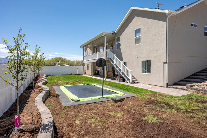 Spacious backyard featuring a manicured lawn area, a white vinyl privacy fence, and a tiered retaining wall