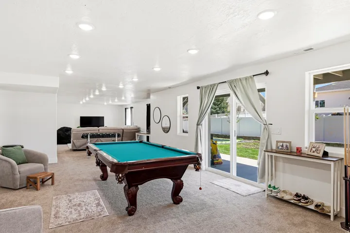 Spacious recreational room with recessed lighting and neutral carpeting