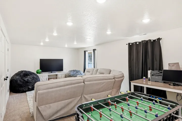 Spacious entertainment room featuring recessed lighting, light-toned carpeting, and white walls