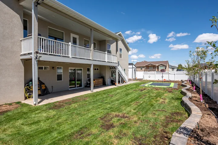 Expansive green lawn with a tiered retaining wall, offering a covered patio and an upper-level balcony