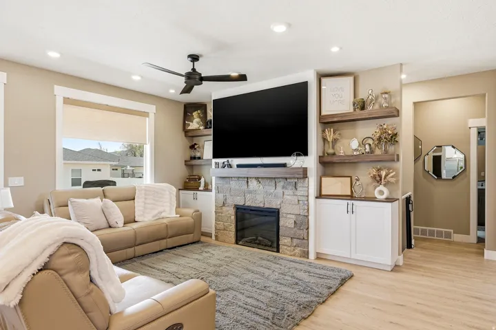 Living area featuring a stone-clad fireplace with a wood mantel, built-in cabinetry, and integrated shelving