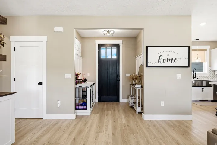 Entryway featuring a dark wood-finish door with glass panels, light wood-finish flooring, and white trim throughout