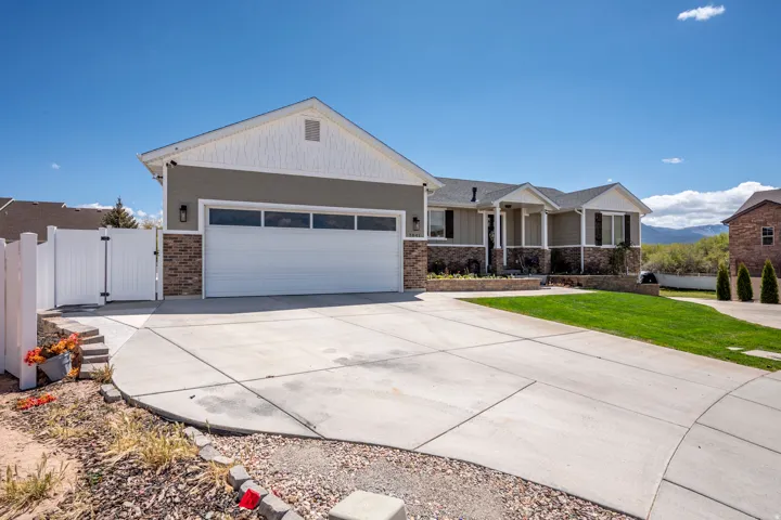 Exterior featuring a two-car garage, concrete driveway, and a white privacy fence