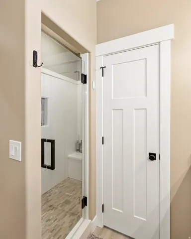 Frameless glass shower enclosure featuring a mosaic tile floor, built-in bench, and black hardware