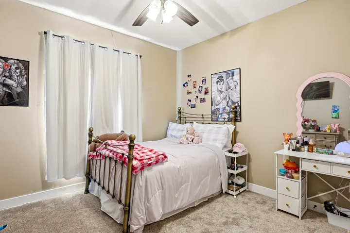 Carpeted room featuring a ceiling fan, window with curtain rods, and neutral wall tones