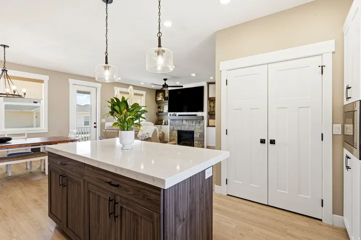 Kitchen island featuring a light-toned countertop, wood-finish cabinetry, and contemporary pendant lighting