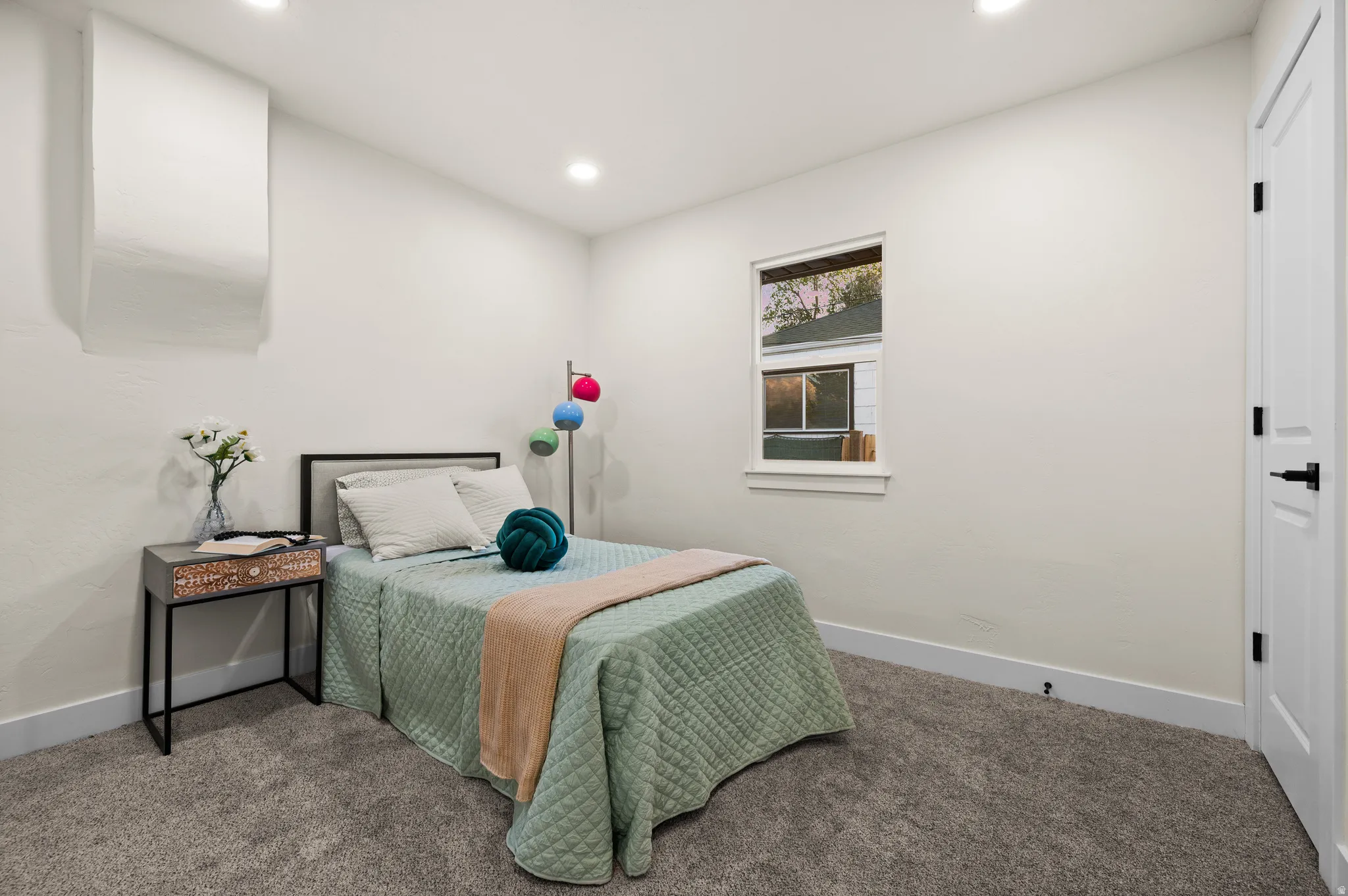 Recessed lighting illuminates the neutral wall tones and plush gray carpeting