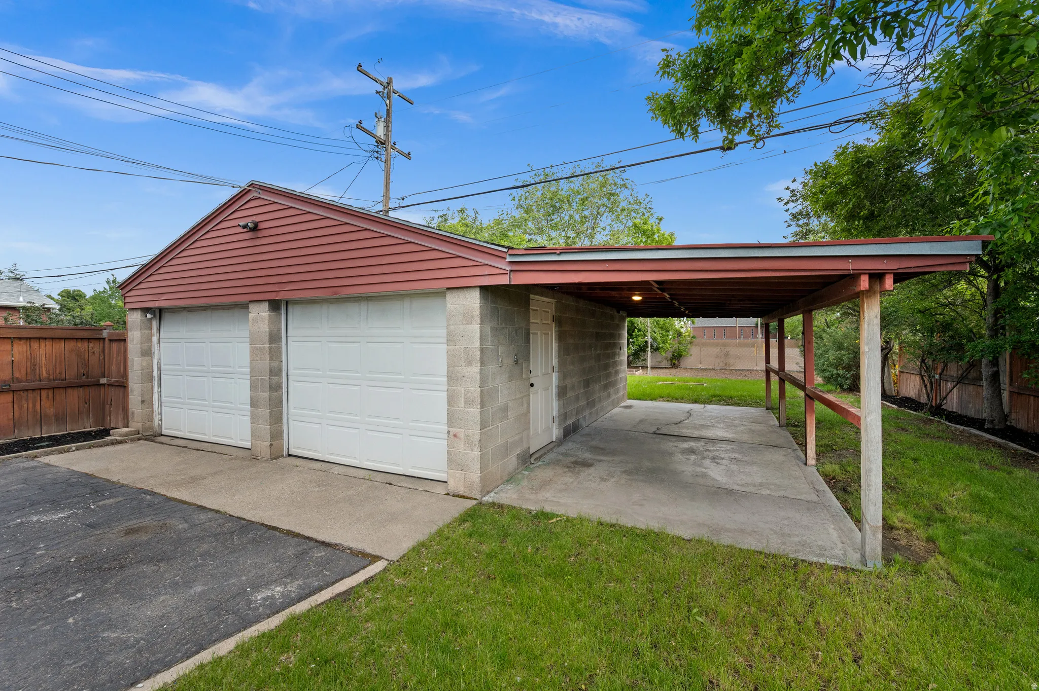 Detached two-car garage with block construction and vinyl siding, featuring two overhead doors and an attached covered carport